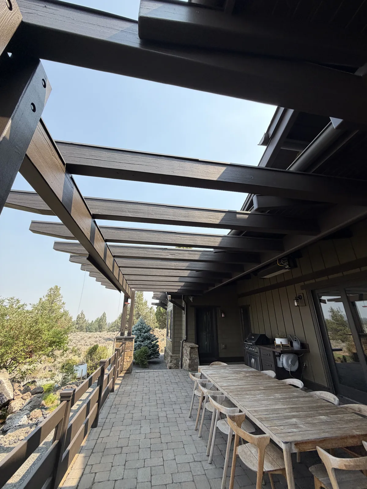 Covered back patio with dark timber beams, paver floor and outdoor dining table
