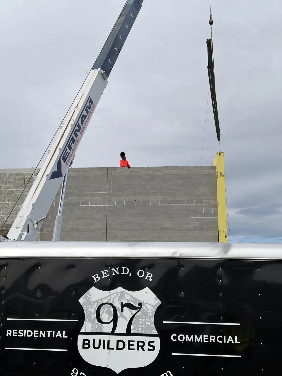 Crane lifting steel above the 97 Builders trailer on the Discount Tire job