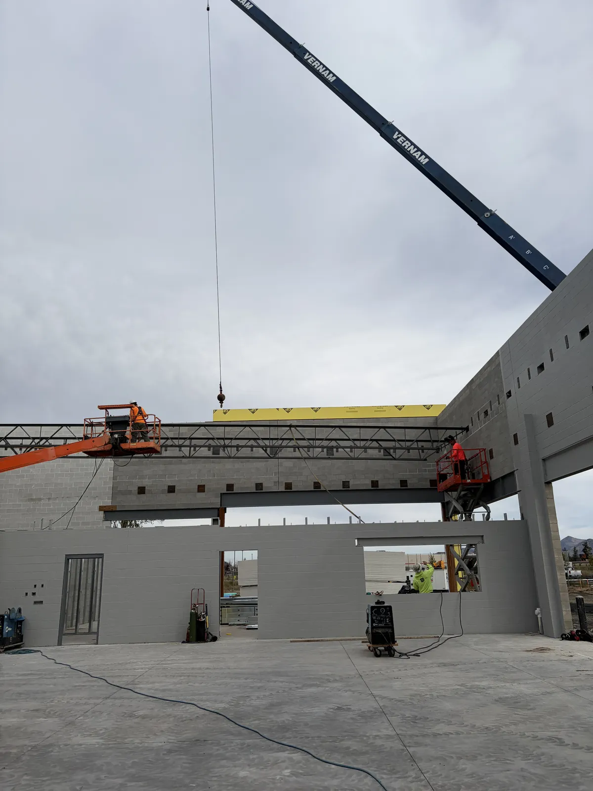 Crew on lifts setting a steel joist at the Discount Tire building