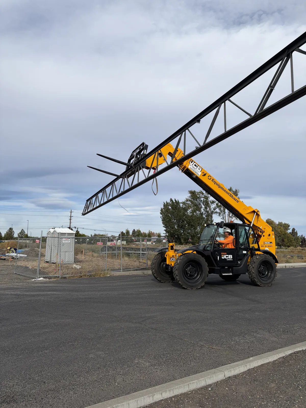Telehandler carrying a steel joist across the Discount Tire site